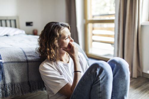 Young adult woman with depression sitting at home alone as she tries to process her grief